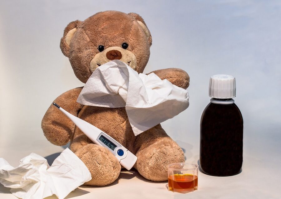 Ein kranker Teddybär mit Taschentuch, Fieberthermometer und Hustensaft